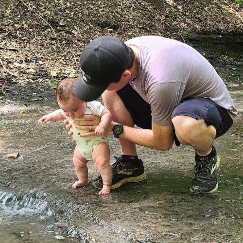 father holding baby in creek