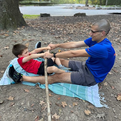 a child and his dad working together on an occupational therapy activity outdoors